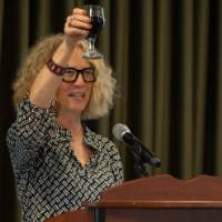 Provost Drake holds up a glass of wine and toasts to the event and guests